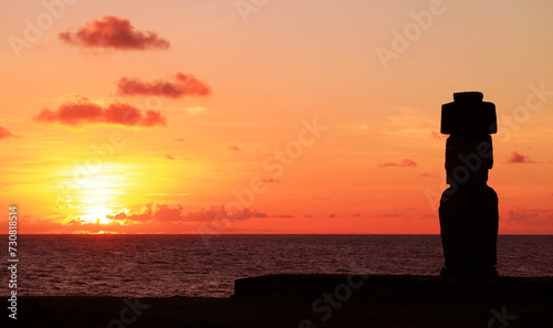 Silhouette of Moai wearing hat called Pukao at Ahu Ko Te Riku ceremonial platform against stunning sunset sky, Pacific ocean, Easter island, Chile, South America photo