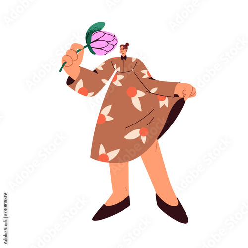 Happy woman holding flower in hand. Girl in dress, smelling spring floral pla...