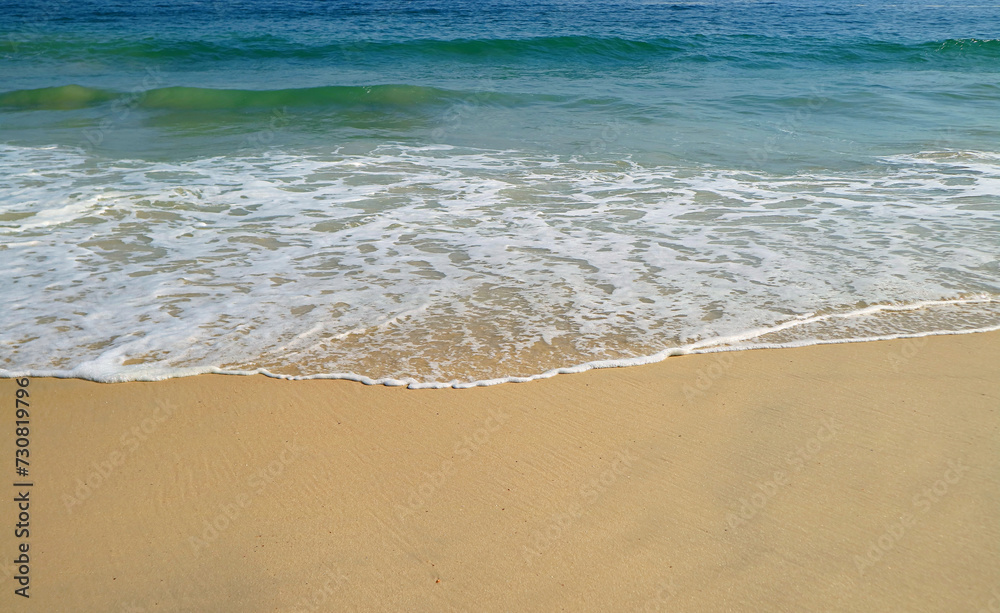 The ocean waves splashing on the sandy beach