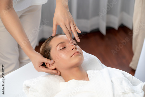 Caucasian woman enjoying relaxing anti-stress head massage and pampering facial beauty skin recreation leisure in dayspa modern light ambient at luxury resort or hotel spa salon. Quiescent