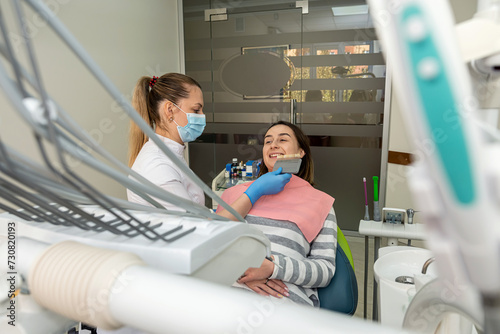 dentist doing correct tooth color with palette with shades of of beauty woman patient