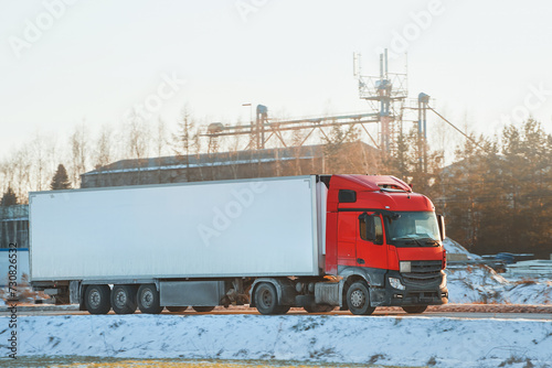 Truck in the winter. Large transport truck transporting commercial cargo in semi-trailer running on the winter snowy road. Snow-covered highway. photo