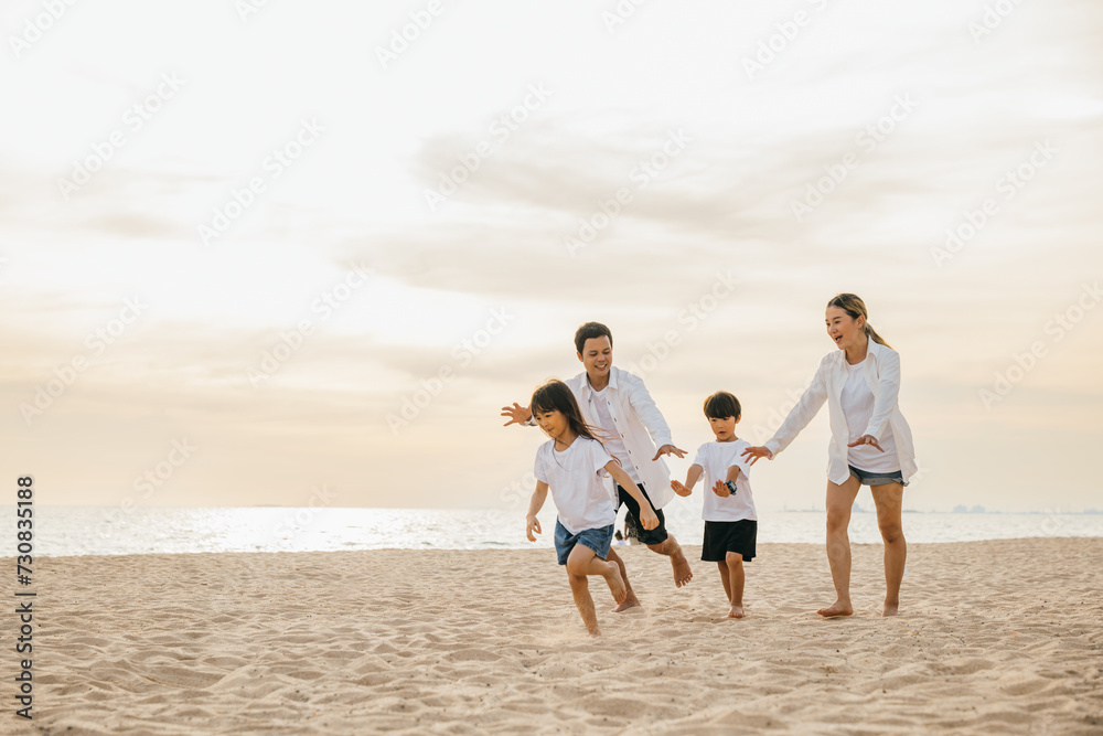 Cheerful family with happy parents and children running on the beach. Laughter fun and joy during summer holiday. Carefree moments of family bonding captured in a snapshot. Family on beach vacation Cheerful family with happy parents and children running on the beach. Laughter fun and joy during summer holiday. Carefree moments of family bonding captured in a snapshot. Family on beach vacation