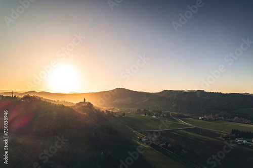 una chiesa troneggia su un tramonto mozzafiato su una grande vallata photo