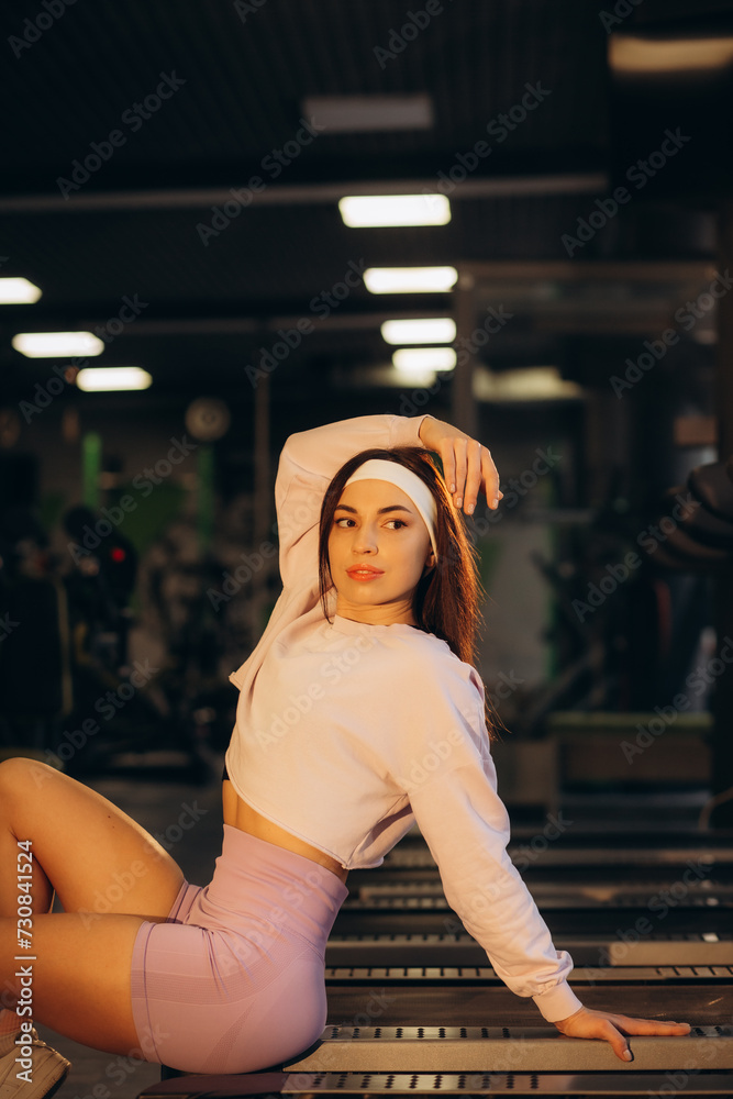 Young sexy fitness girl in sport wear relaxing on the treadmill in the gym, woman exercise working out sitting on runnig machine Young sexy fitness girl in sport wear relaxing on the treadmill in the gym, woman exercise working out sitting on runnig machine