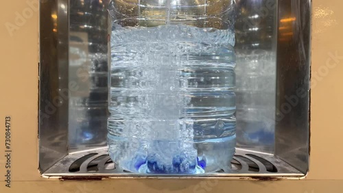 Drinking water bottling process. A five-liter plastic bottle in a drinking water vending machine. Close-up. The bottle is filled with drinking water. Water for drinking and cooking is healthy.