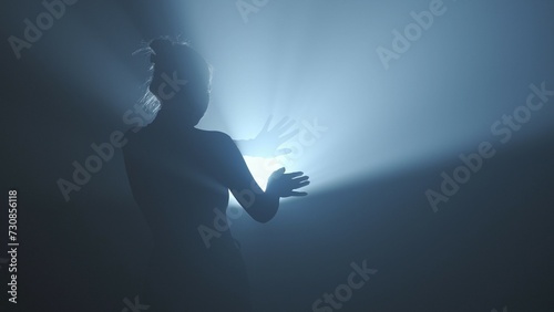 Photography Female model against bright backlight on black smoky background in studio
