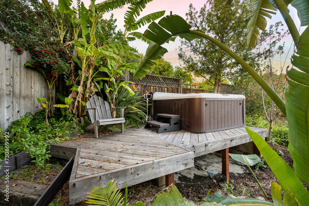 Wooden deck featuring an outdoor hot tub surrounded by lush greenery