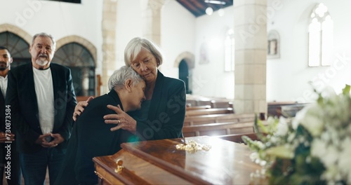 Senior women, hug and funeral in church for comfort, support and care with crying, sad and religion. Family, friends and embrace for death, loss and console with love, empathy and faith by coffin photo