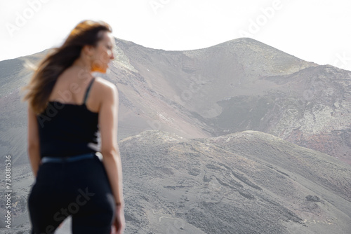 woman standing sideways with hair blowing in the wind in a volcano