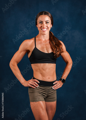 Smiling muscular female fitness model posing