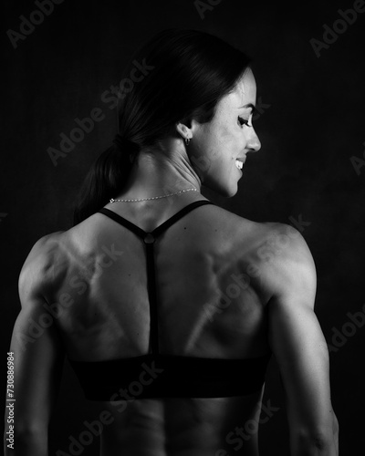 Black and white image of a female fitness model posing her muscular back 