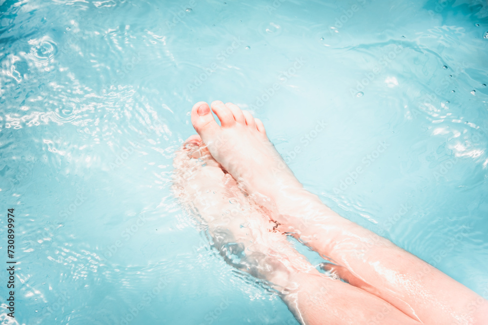Fototapeta premium Child bare feet under blue water in a swimming pool.