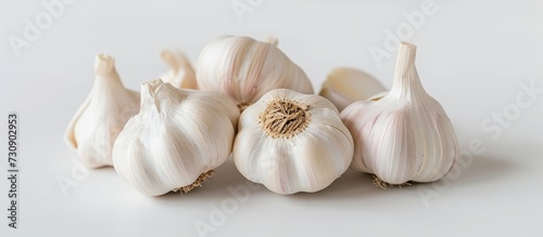 A pile of garlic bulbs, a natural ingredient and flowering plant, arranged on a white surface.