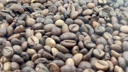 Close-up of coffee seeds. Roasted aromatic coffee beans with smoke emanating from the beans. Industrially prepared hot coffee, organic freshness.