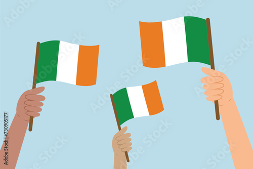 Diverse hands raising flags of Ireland. Vector illustration of Irish flags in flat style on blue background.