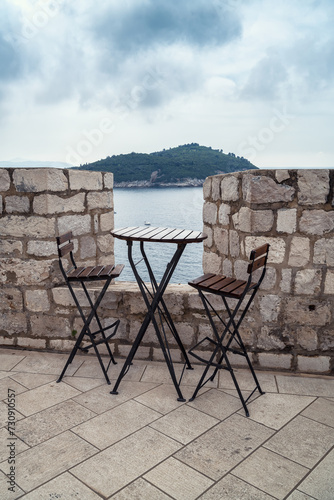 Table and high chairs in a cafe located on the city walls of the old town of Dubrovnik overlooking the island of Lokrum, Croatia