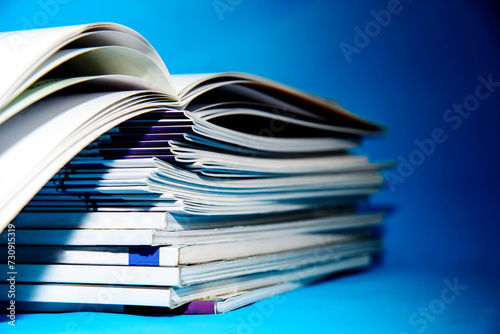 Stack of magazines on a blue background, isolated in a university library Education concept