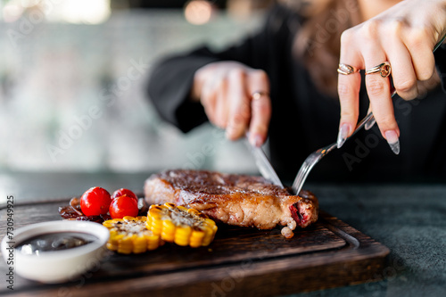 Fototapeta Naklejka Na Ścianę i Meble -  woman hands with fork and knife eating beef steak in cafe
