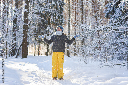 11 year old happy boy walks in the winter forest, watches the snowfall on a sunny day. photo