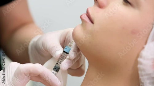In a medical office, a cosmetologist gives beauty injections to a young woman’s chin. The concept of modern procedures in cosmetology.