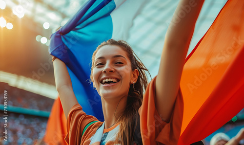 An excited female sports spectator holding a france flag in a sports stadium