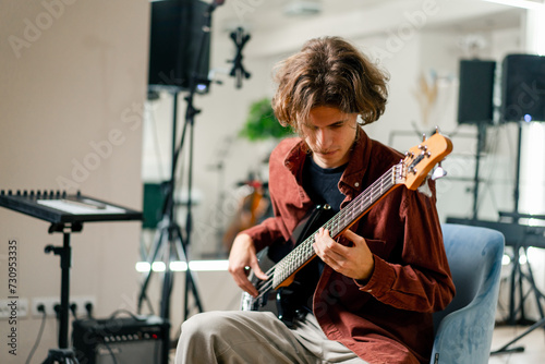 rock artist with long hair with electric guitar in recording studio playing own track musical instrument string melodies