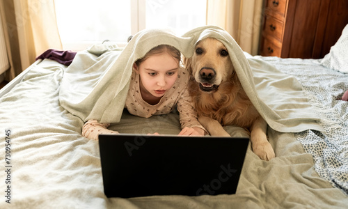 Joyful Little Girl Playing With Golden Retriever Dog, Covered By Blanket And Working With Laptop