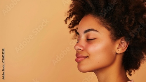 A close-up portrait of a young woman with a radiant complexion closed eyes and a serene expression set against a warm soft-focus background.
