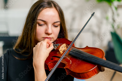 Close-up of a girl holding a violin picking strings with a bow to perform a classical music composition