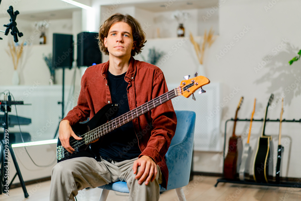 Obraz premium portrait of a young musician with long hair holding an electric guitar in his hands in a recording studio