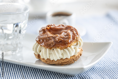 Veternik - sweet donut, typically Slovak caramel sweet cake with cream filling topped with caramel on a plate in a cafe