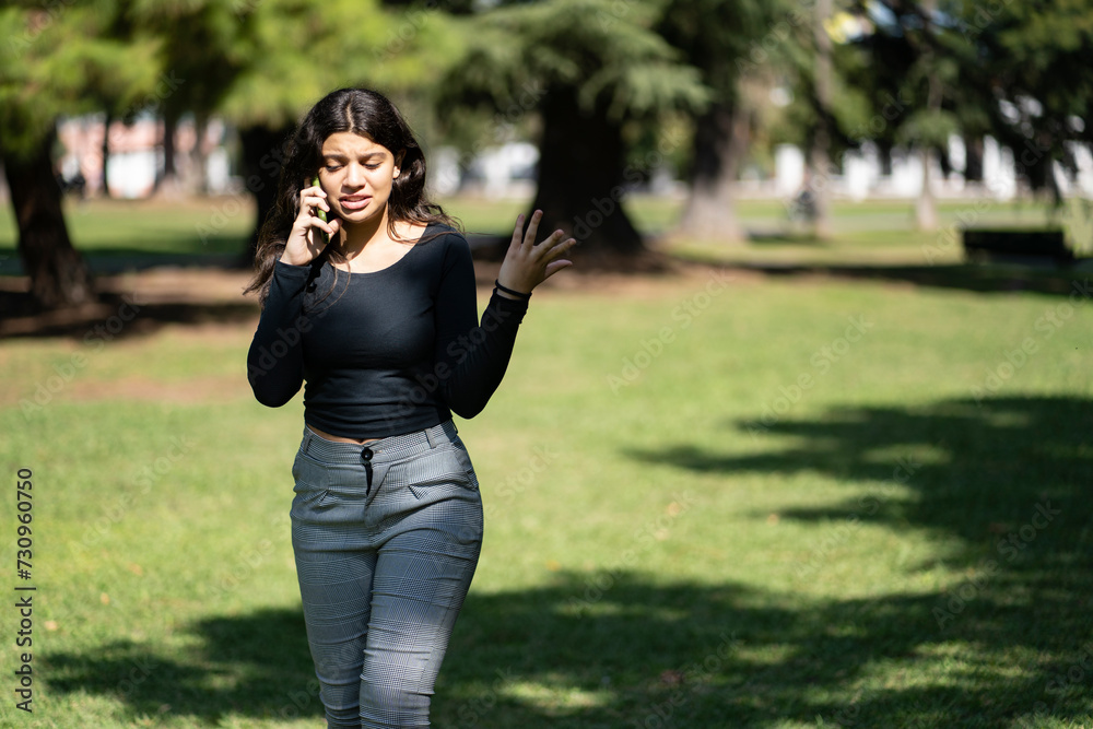 Latin teen girl talking on the phone in a park Latin teen girl talking on the phone in a park