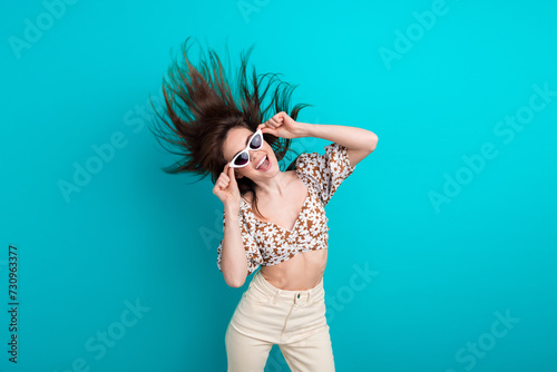Photo of girlfriend young fashionista touching her gucci sunglasses shaking head flying hair and dance isolated on cyan color background
