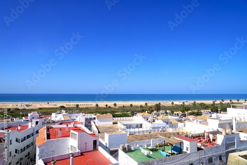view from the Torre de Guzman tower over the roofs of Conil de la Frontera towards the dunes and beautiful beach Playa los Bateles at the Atlantic Ocean, Costa de la Luz, Andalusia, Spain photo