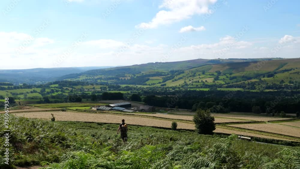 A couple, two hikers walking down footpath in the beautiful Derbyshire countryside, man carrying child in the backpack carrier. A couple, two hikers walking down footpath in the beautiful Derbyshire countryside, man carrying child in the backpack carrier.