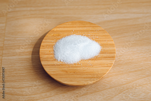 A pile of salt on a jar lid with a wooden background.