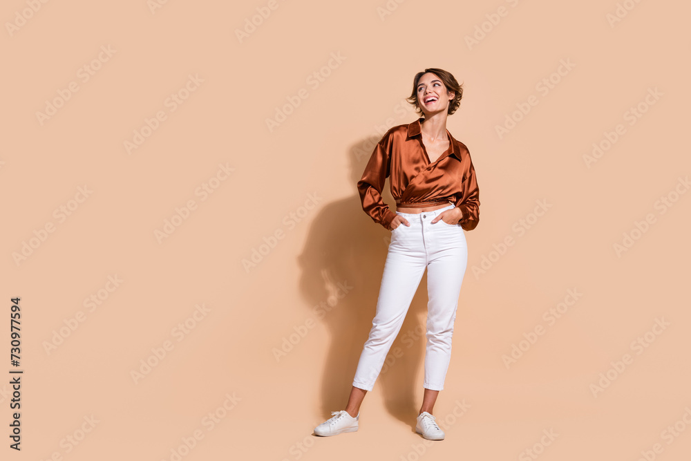 Full length photo of good mood dreamy woman wear silky blouse looking empty space isolated beige color background Full length photo of good mood dreamy woman wear silky blouse looking empty space isolated beige color background