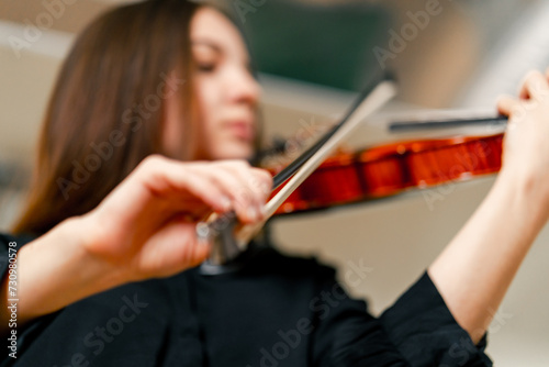 Close-up of a girl holding a violin with her fingers, fingering the strings to perform a classical musical composition
