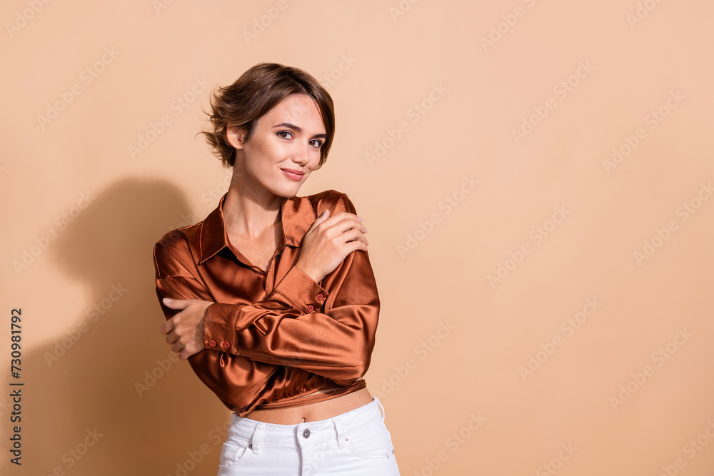 Photo of adorable sweet girl wear brown blouse cuddling herself empty space isolated beige color background Photo of adorable sweet girl wear brown blouse cuddling herself empty space isolated beige color background