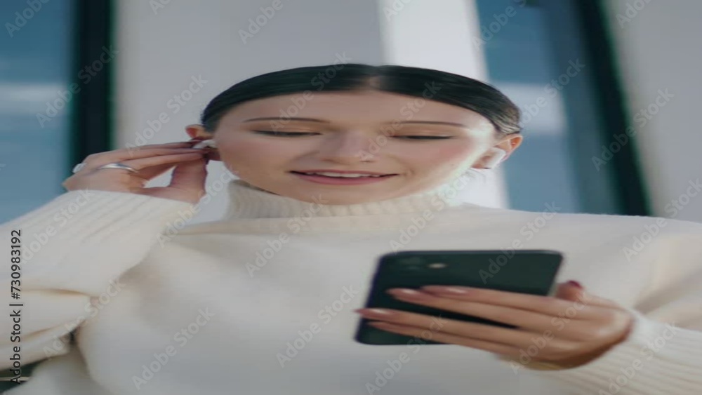 Woman making video call by smartphone wearing wireless headset close up vertical Woman making video call by smartphone wearing wireless headset close up vertical