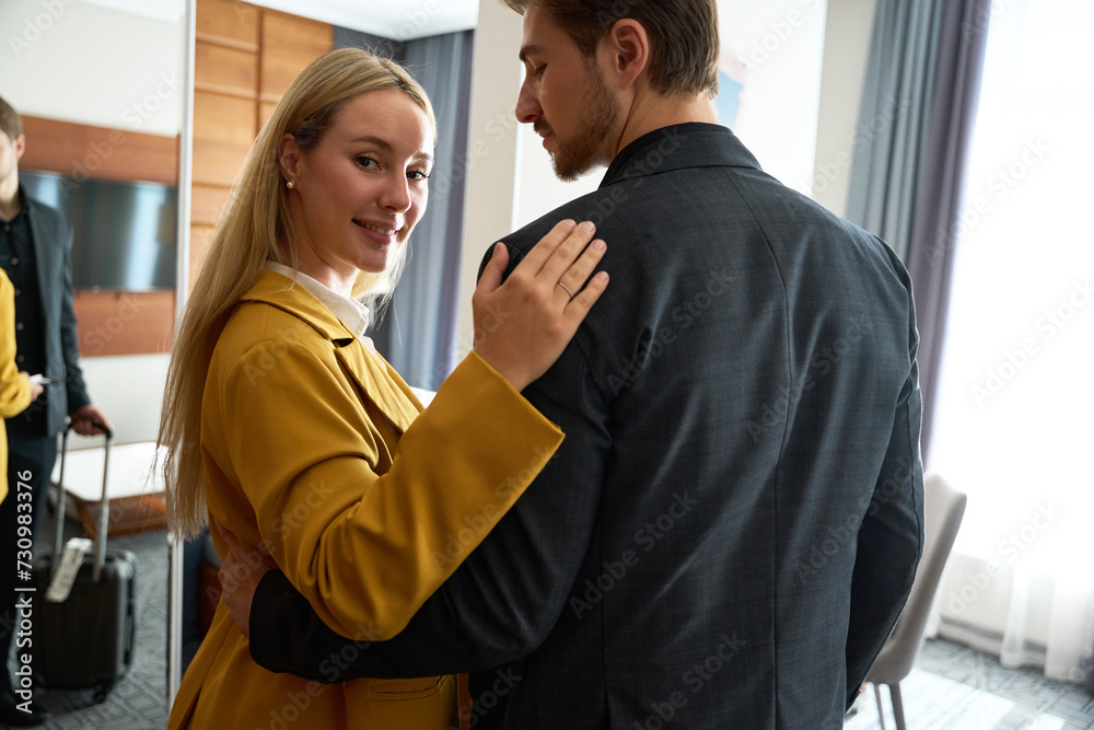 Newlyweds in travel suits stand hugging each other in hotel room Newlyweds in travel suits stand hugging each other in hotel room