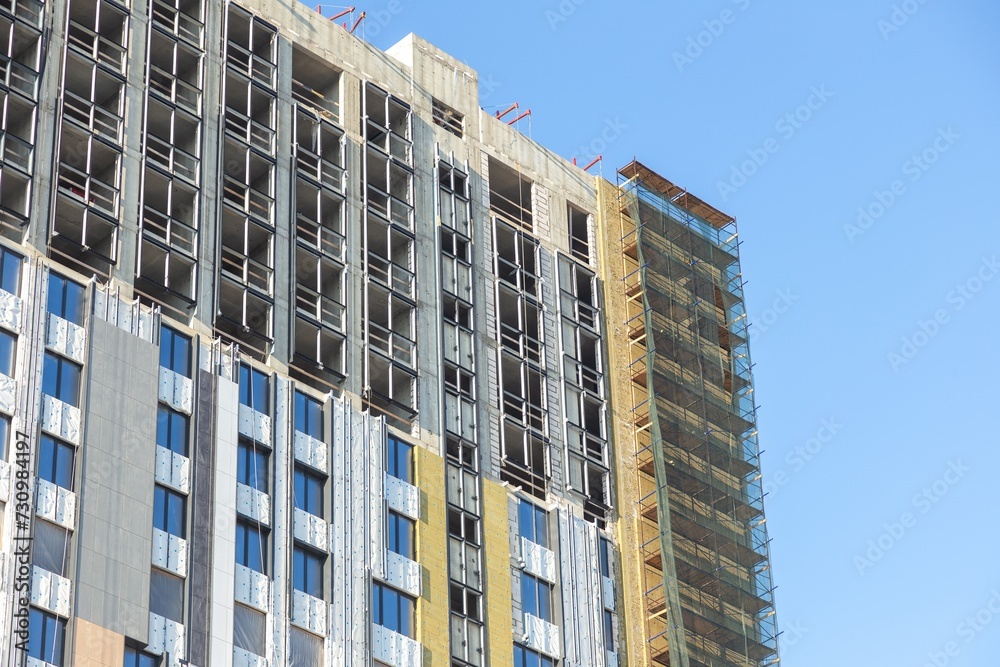 Fototapeta premium Modern Building Under Construction with Insulation Layers Exposed Facade Works