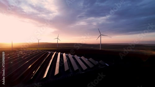 Solar panels park and wind turbines at sunset.Windmill turbines generating green energy electric.Green energy  reduce carbon emissions and makes earth cleaner and more ecological. photo