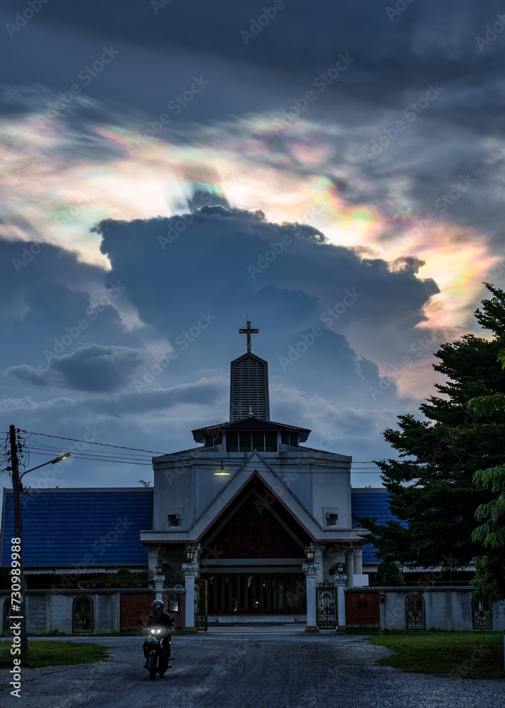 Mysterious cloud iridescence phenomenon glowing over christian church in the evening