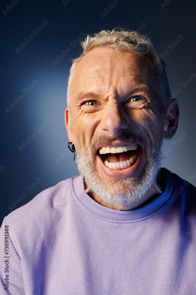 cheerful mature man with gray beard and casual trendy attire grimacing and looking at camera cheerful mature man with gray beard and casual trendy attire grimacing and looking at camera