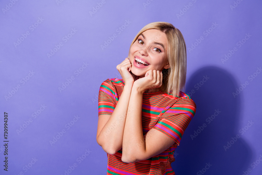 Portrait of astonished ecstatic young girl blonde bob hairdo wear trendy t shirt palms on cheekbones isolated over purple color background