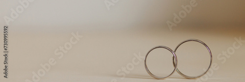 Wallpaper Mural Two gold wedding rings intertwined on a neutral beige surface, symbolizing unity and eternal love. Ideal for wedding or anniversary concepts. Banner with copy space. Torontodigital.ca