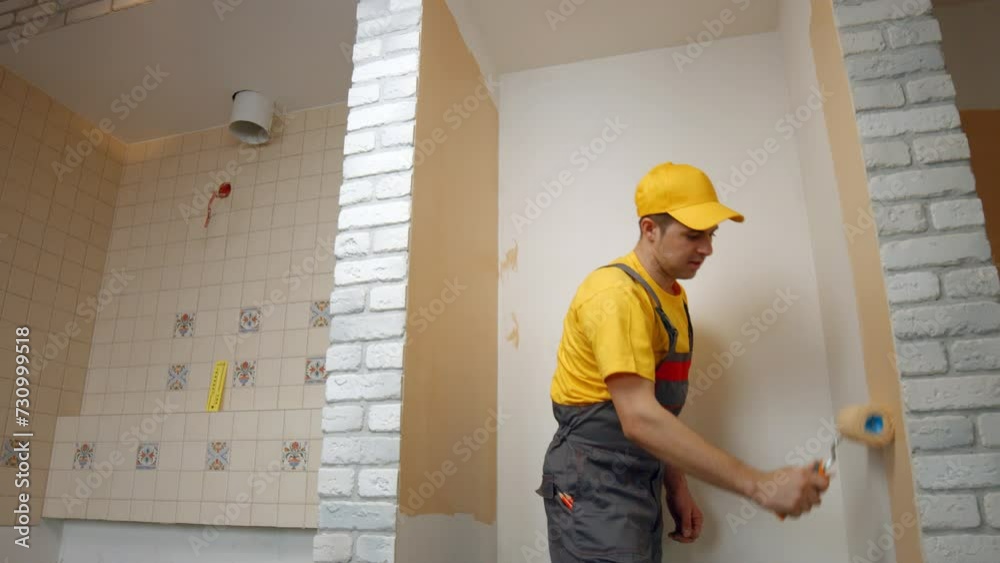 House painter paints the wall in beige color. Worker paints the wall roller. House painter paints the wall in beige color. Worker paints the wall roller.
