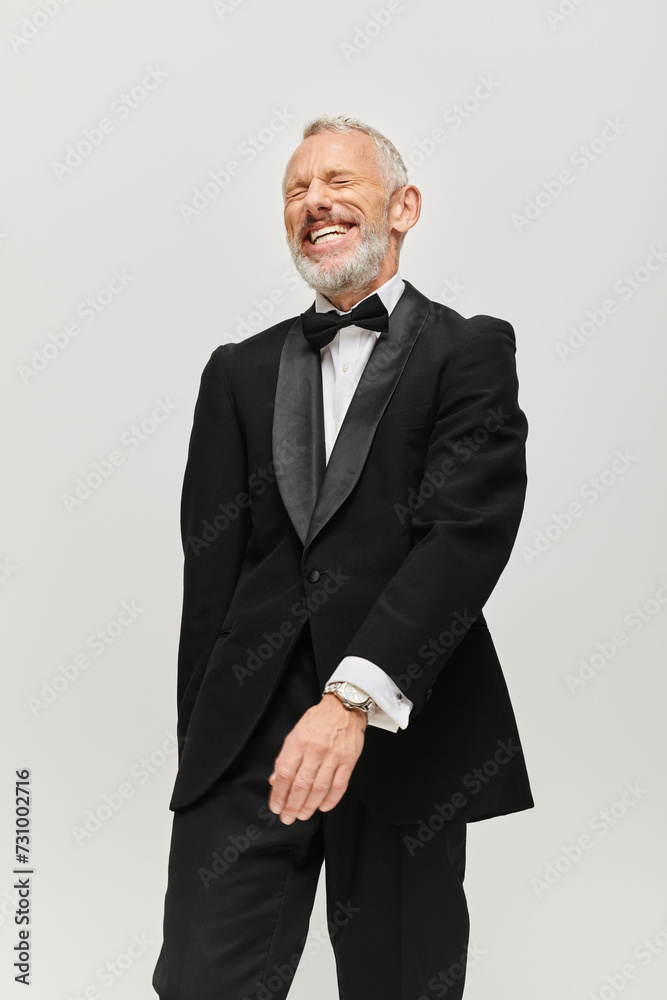joyful good looking mature man with bow tie and gray beard in chic tuxedo smiling happily joyful good looking mature man with bow tie and gray beard in chic tuxedo smiling happily